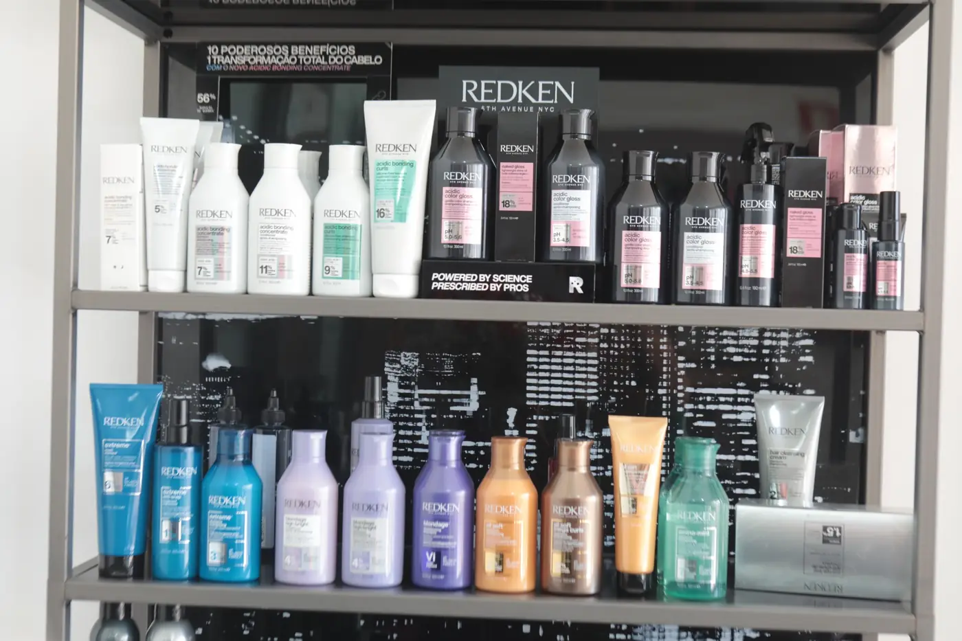 Prateleiras do salão com a gama Redken: Acidic Bonding, Acidic Color Gloss, Extreme, Blondage e outras